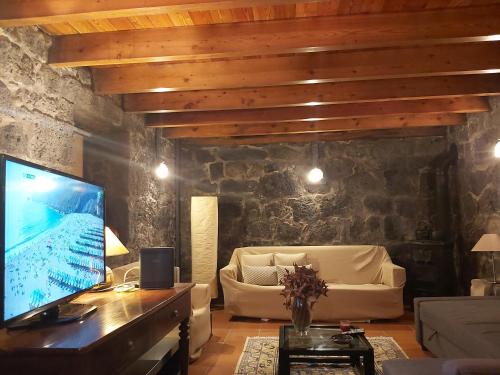 a living room with a couch and a tv at CASA DO CANAL in São Roque do Pico