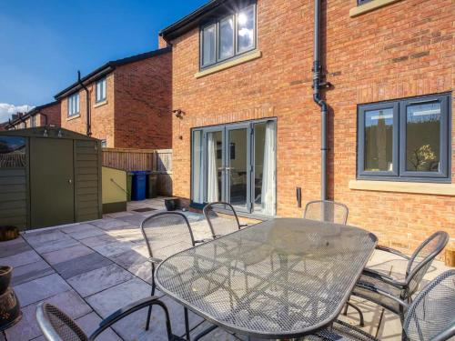 a glass table and chairs on a patio at Pass the Keys Modern Manchester House with Airport Links in Cheadle