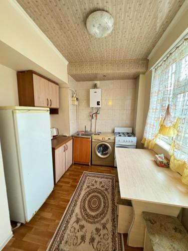 a small kitchen with a refrigerator and a table at Двухкомнатная 67 квартира в центре in Shymkent