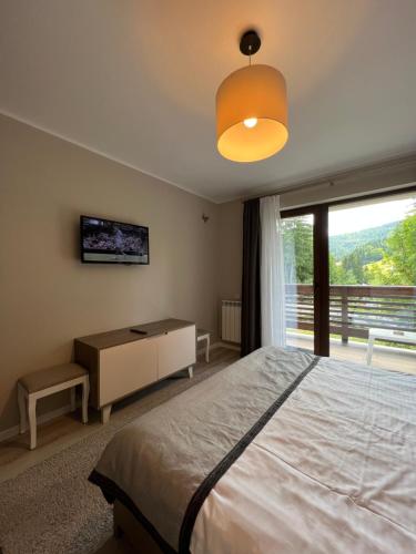 a bedroom with a bed and a large window at Apartamente de inchiriat- Garden Apart Predeal in Predeal