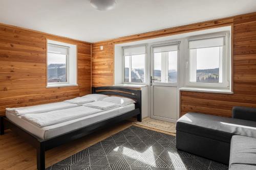1 dormitorio con cama, sofá y ventanas en Woodvel House en Palyanytsya