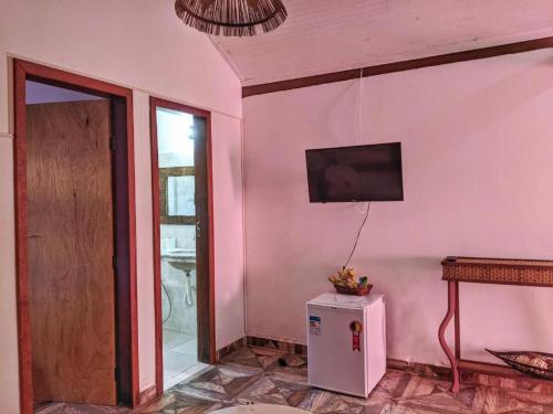 Habitación con nevera pequeña y TV en la pared. en Pousada Nova Papa Terra, en Itacaré