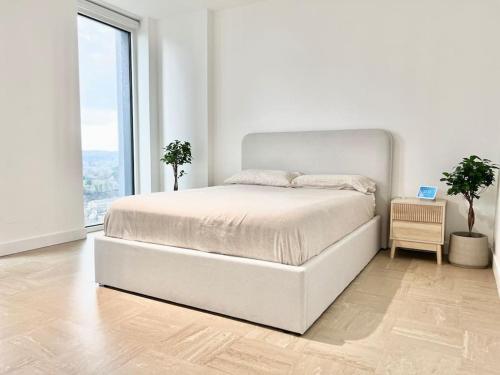 a white bedroom with a bed and a large window at Short term apartment in London in London