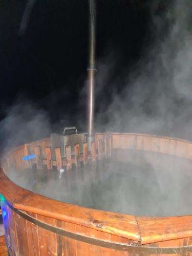 a hot tub in a wooden barrel with smokes at Cabana Dealu Capsei in Cîmpeni