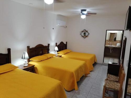 two beds in a room with yellow sheets at Hotel Bellota in Parras de la Fuente