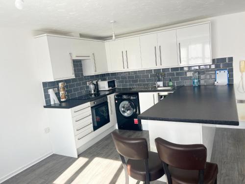 a kitchen with white cabinets and a black counter top at Comfortable and Cosy London Stay in London