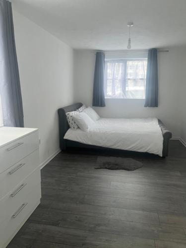 a bedroom with a bed and a window with blue curtains at Comfortable and Cosy London Stay in London