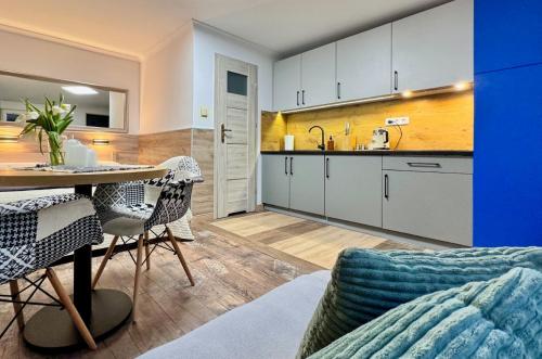 烏斯特卡的住宿－Apartamenty Marea Rentals Beniowskiego Ustka，厨房以及带桌椅的起居室。