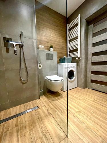 a bathroom with a toilet and a washing machine at Apartament Rejs in Ostróda