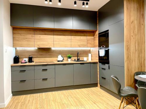 una cocina con armarios grises y de madera y una mesa. en Apartament Rejs, en Ostróda