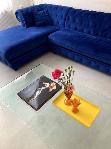 a living room with a blue couch and a glass table at Lovely, light and calm 1-bedroom apartment in Amsterdam