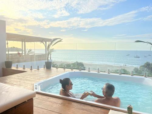 a man and woman sitting in a jacuzzi in a swimming pool at PUNTA VELEROS ROOFTOP in Los Órganos