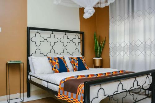 a bedroom with a bed with an orange and white comforter at Naalya Motel in Kampala