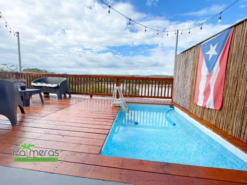 a swimming pool on a deck with an american flag at Palmeras Beach Apartments - Playa Santa in Guanica