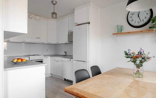 cocina con mesa y reloj en la pared en Bright and spacious condo near subway with FREE parking, en Espoo