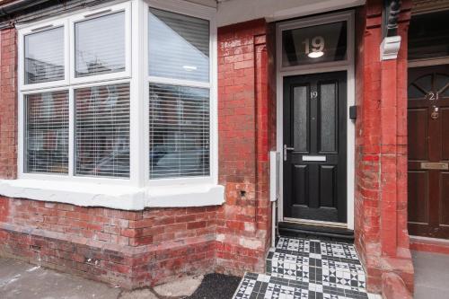 een bakstenen huis met een zwarte deur en ramen bij Ashley’s Place in Manchester