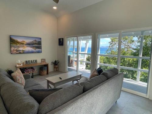 a living room with a couch and a large window at Sea Cave - Listen to the ocean from your bedroom! in Calabash Boom