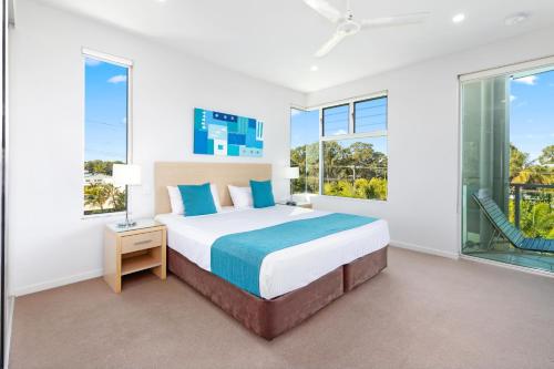 a bedroom with a large bed and large windows at Akama Resort in Hervey Bay