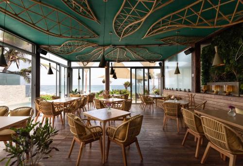 a restaurant with tables and chairs and a green ceiling at Mi Amor by La Zebra, an SLH Hotel in Tulum