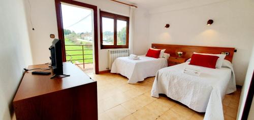 a hotel room with two beds and a television at Sidreria La Casa Abajo in La Franca