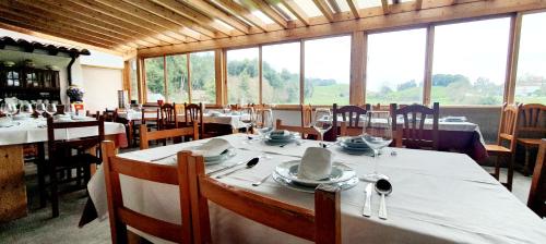 a dining room with tables and chairs and windows at Sidreria La Casa Abajo in La Franca
