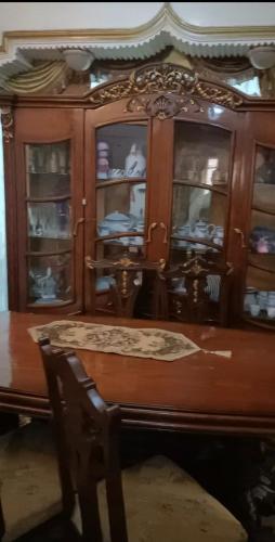 un armario de madera con puertas de cristal, una mesa y una silla en Ema en El Cairo