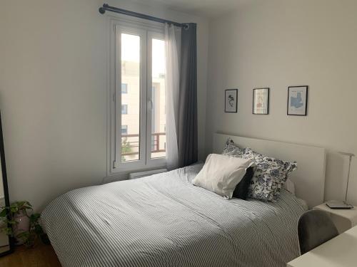 a bed in a bedroom with a window at Appartement moderne metro 9 in Boulogne-Billancourt