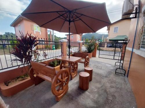 um pátio com uma mesa, um banco e um guarda-chuva em Cozy Corner at Camella Subic Vista Estates em Subic