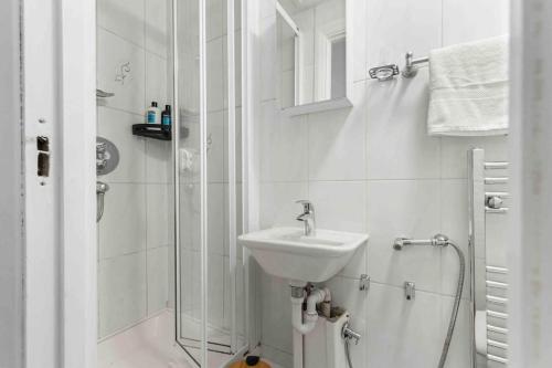 a white bathroom with a sink and a shower at Hyde Park/Paddington Flat in London