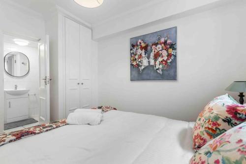 ein Schlafzimmer mit einem weißen Bett und einem Gemälde an der Wand in der Unterkunft Hyde Park/Paddington Flat in London