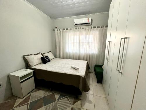 um pequeno quarto com uma cama e um frigorífico em Loft 05 Excelente Localização em Cuiabá