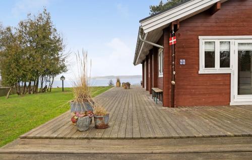 a wooden deck with two potted plants and a building at Cozy Home In Holbæk With House Sea View in Holbæk