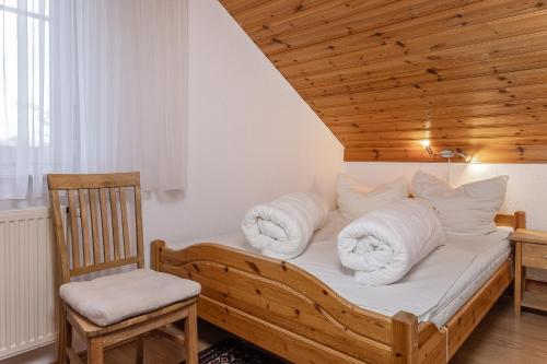 Cette chambre comprend un lit avec des oreillers blancs et une chaise. dans l'établissement 50005 Ferienhaus Louis, à Carolinensiel