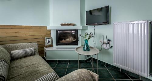 a living room with a couch and a tv and a table at Nymfes in Tsagarada