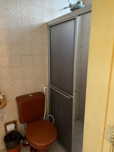 a bathroom with a toilet with a glass shower door at Apartamento Aluguel Morro Branco. in Beberibe