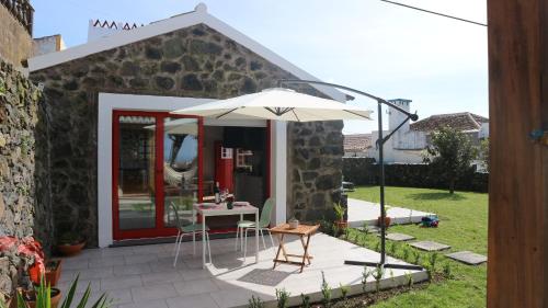 a patio with a table and an umbrella at Casa do Poço in Santa Bárbara