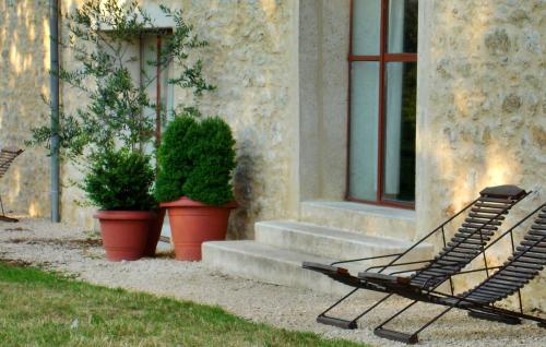 une chaise assise à l'extérieur d'un bâtiment avec des plantes en pot dans l'établissement Lescalparède, à Florimont-Gaumiers