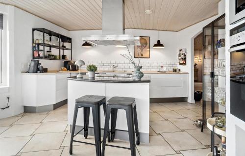 a kitchen with two stools at a kitchen counter at 5 Bedroom Cozy Home In Thyborøn in Thyborøn