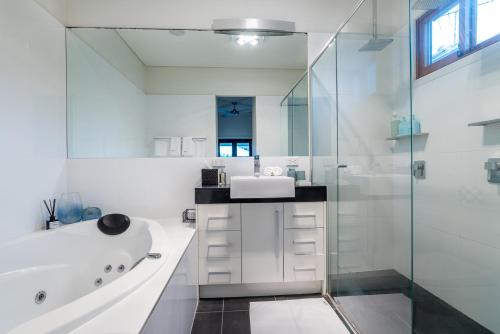 a white bathroom with a tub and a sink at Beautiful Modern Home in Heart of New Farm in Brisbane