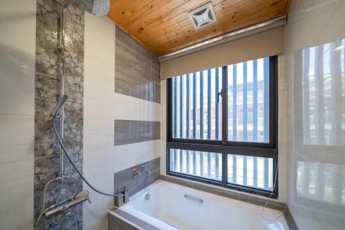 un bagno con vasca e finestra di 享樂民宿 可包棟 a Ji'an