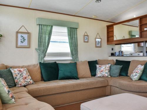 uma sala de estar com um grande sofá castanho com almofadas em Skiddaw View Lodge em Plumbland
