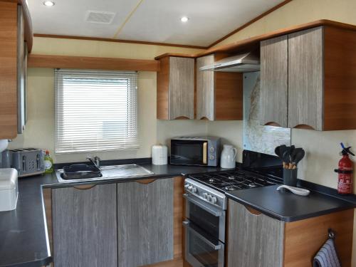 a kitchen with a stove and a microwave at Skiddaw View Lodge in Plumbland