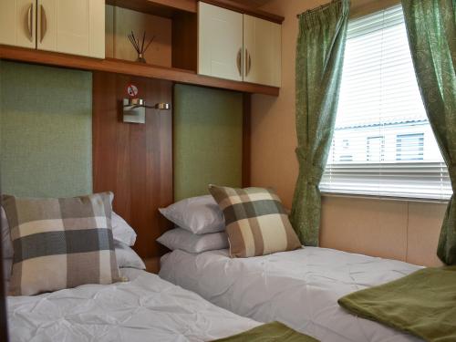 two beds in a room with a window and a window at Skiddaw View Lodge in Plumbland