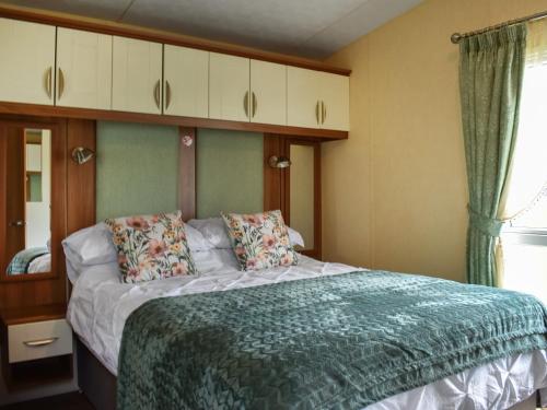 a bedroom with a bed with a green comforter at Skiddaw View Lodge in Plumbland