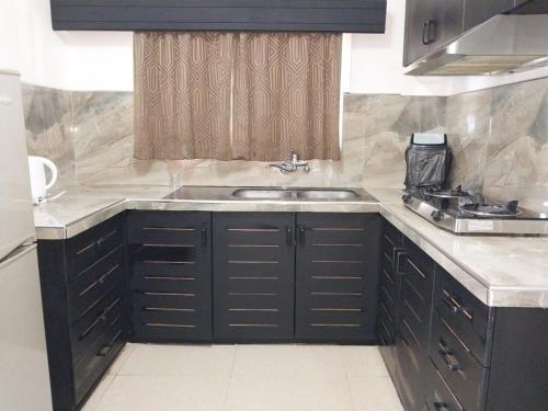 a kitchen with black cabinets and a sink at Holiday Hire Fiji in Lautoka