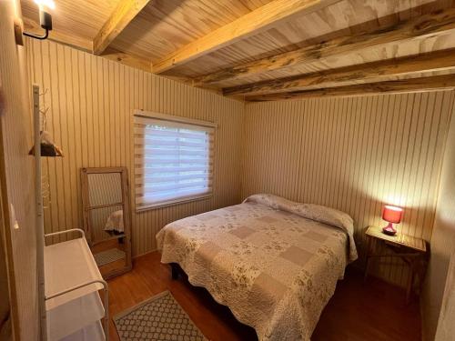 a small bedroom with a bed and a window at Cabañas Los Maitenes in Freire