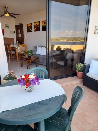 uma mesa e cadeiras com um vaso de flores em Seafront Maisonette Ocean Views & Terrace em Mellieħa