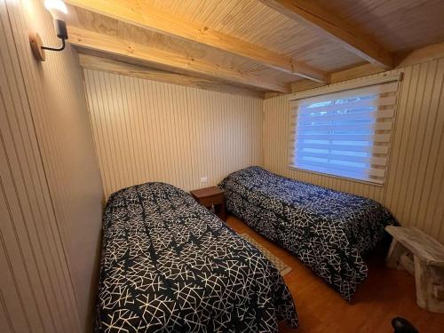 Cette petite chambre comprend 2 lits et une fenêtre. dans l'établissement Cabañas Los Maitenes, à Freire