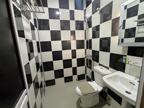a black and white bathroom with a toilet and a sink at Tambun Warm Hotel in Ipoh