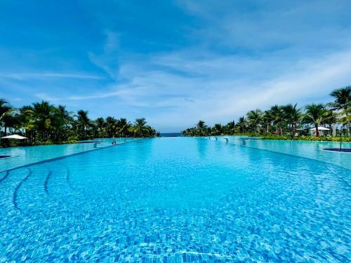 a large swimming pool with palm trees in the background at THE CAM RANH RESORT at Bai Dai in Cam Ranh